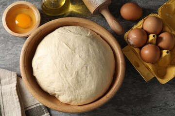 Raw dough, rolling pin and ingredients on grey table, flat lay