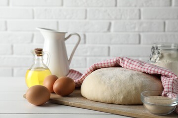 Raw dough and ingredients on white wooden table