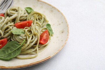 Tasty pasta with spinach and tomatoes on light table, closeup. Space for text