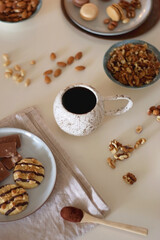 Cup of tea or coffee, cookies, macaroons, chocolate, various nuts and cocoa powder on white background. Selective focus.