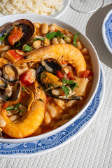 A traditional Alentejo restaurant serves a vibrant seafood feijoada. This dish features prawns, shellfish, and beans in a rustic clay pot, offering a hearty and authentic Portuguese experience.