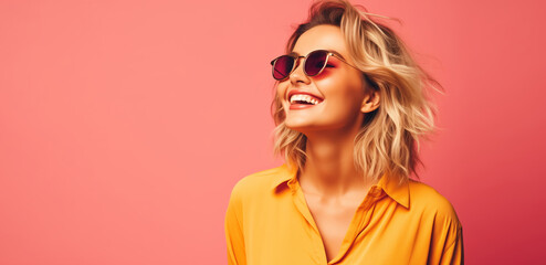 Summer portrait of happy stylish smiling young woman in sunglasses, yellow shirt on pink background