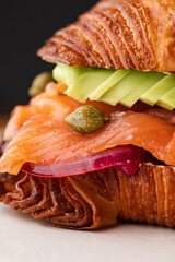 Close-Up of the filling of a Croissant Sandwich: Flaky Croissant Stuffed with Fresh Smoked Salmon,...