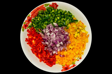 Vegetable salad. Arrangement on plate with onion, corn, mango, tomato, green pepper and red pepper. Black background. Horizontal.
