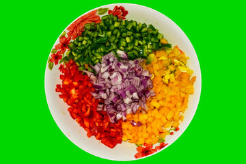 Vegetable salad. Arrangement on plate with onion, corn, mango, tomato, green pepper and red pepper. Green background. Horizontal.
