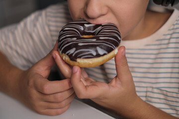 A child enjoys a delicious donut while wearing headphones, illustrating the pleasures of a sweet...