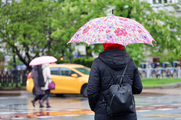 Woman with umbrella on city street on taxi car background. Rainy weather in spring