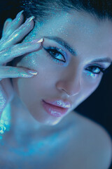 Woman with striking blue and silver beauty makeup posing for the camera