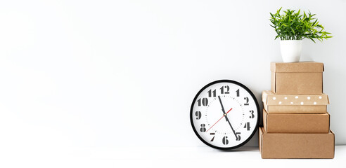 A classic black clock and a potted plant on a white table with a white background and space to copy