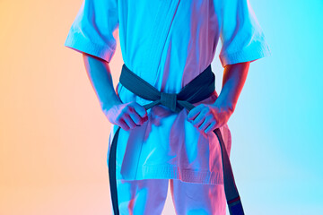 Cropped image of boy, karate athlete in uniform, white kimono and green belt standing against...