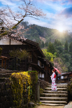 Asian girl in traditional Japanese kimono visits Tsumago juku Preserved town of Nakasendo with cherry blossom in spring, Famous travel destination in Chubu, Japan.
