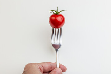 Hand Holding a Fresh, Ripe Tomato on a Fork