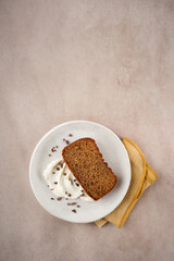Cake slice topped with whipped cream on a cream background, with copy space. Top view. Birthday loaf cake concept.