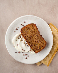 Cake slice topped with whipped cream on a cream background, with copy space. Top view. Close Up. Birthday loaf cake concept.