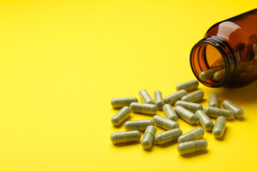 Vitamin pills and bottle on yellow background, closeup. Space for text