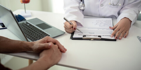 Doctor consulting male elderly patient filling medical form. Professional physician writing information in clipboard checking examining elderly man during appointment visit in clinic