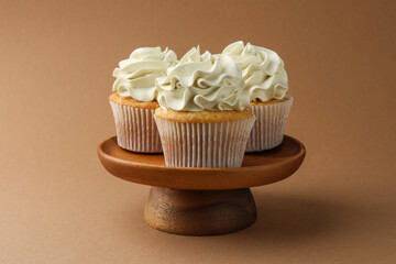 Tasty vanilla cupcakes with cream on dark beige background