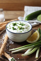 Delicious yogurt, green onion, grissini and lemon on table