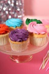 Delicious cupcakes with bright cream on pink table, closeup