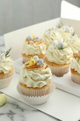 Tasty Easter cupcakes with vanilla cream on white marble table, closeup