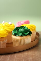 Delicious cupcakes with bright cream on wooden table, closeup