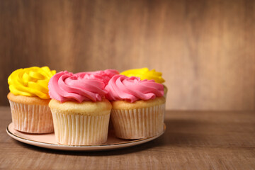 Delicious cupcakes with bright cream on wooden table, closeup. Space for text