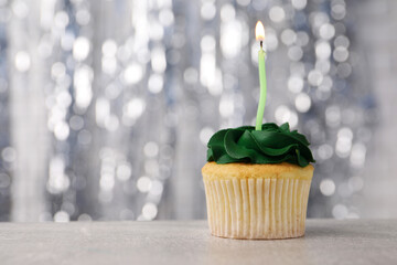 Delicious cupcake with bright cream and burning candle on grey table, closeup. Space for text