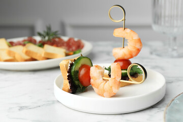 Tasty canapes with shrimps, cucumber, greens and tomatoes on white marble table