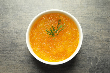 Fresh pike caviar and dill in bowl on grey table, top view