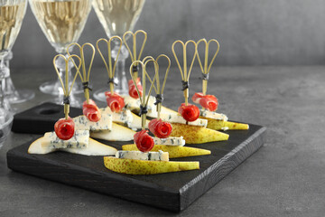 Tasty canapes with pears, blue cheese and prosciutto on grey table, closeup. Space for text