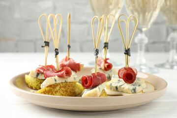 Tasty canapes with pears, blue cheese and prosciutto on white wooden table, closeup
