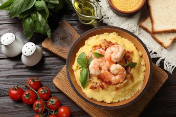 Fresh tasty shrimps, bacon, grits and basil in bowl on wooden table, flat lay
