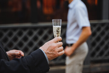 Man gesturing with glass of champagne at another man at event