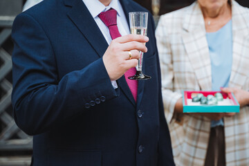 A gentleman in a blazer and tie raises a glass of champagne