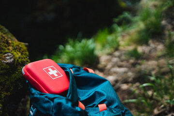 Electric blue backpack with red first aid kit on top in natural landscape