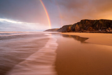 Sandymouth Bay, early morning light and rainbow at low tide, north Cornwall, UK. December 2020. 