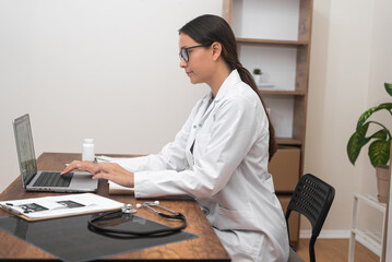 Telehealth in Action: A committed female doctor, fixated on her laptop, offers medical guidance and...