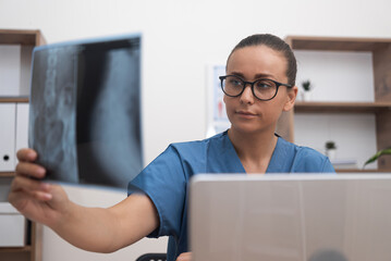 doctor in a blue scrubs uniform meticulously examines a radiology X-ray film, rendering healthcare...