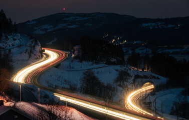 Long exposure of traffic on the highway and train passing in the winter night

