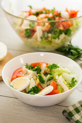 fresh vegetable salad, cabbage, tomatoes in a bowl on a wooden table