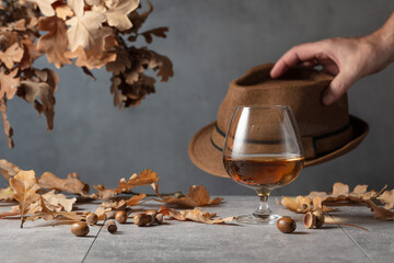 Snifter of brandy on a stone table with dried-up oak leaves.