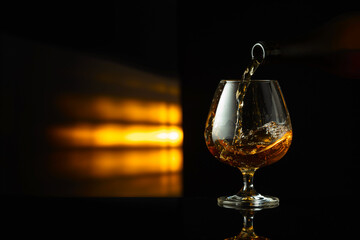 Pouring brandy from a bottle into a snifter.