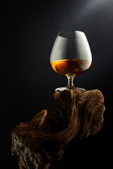 Snifter of brandy on a old wooden snag.