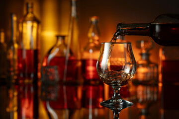 Pouring brandy from a bottle into a glass.