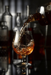 Pouring brandy from a bottle into a glass.