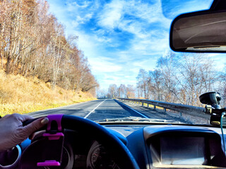 Car salon, windshield, hand of woman on steering wheel and landscape. View from seat of driver on nature. Single trip of female traveler