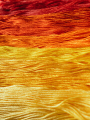 Floss threads of warm colors in close-up.