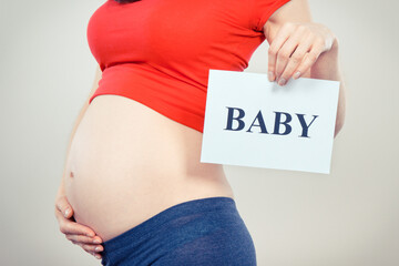 Pregnant woman holding card with inscription baby. Expecting birth of newborn. Extending family