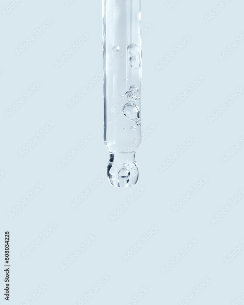 Wall mural glass pipette filled with cosmetic serum close-up on a blue background