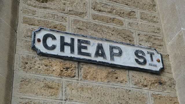 Close up of a old vintage street sign for Cheap st against rustic brick wall in the market town of Frome, Somerset, England